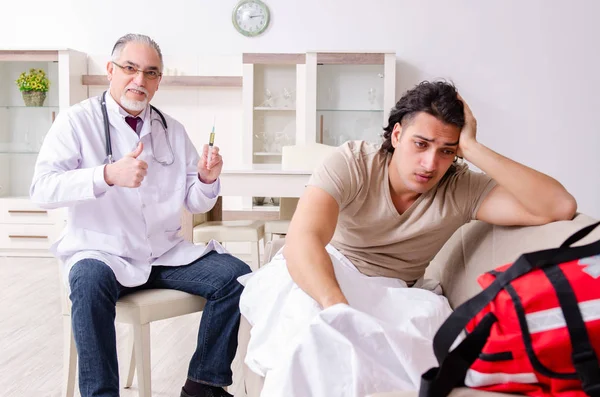 Old male doctor visiting young male patient