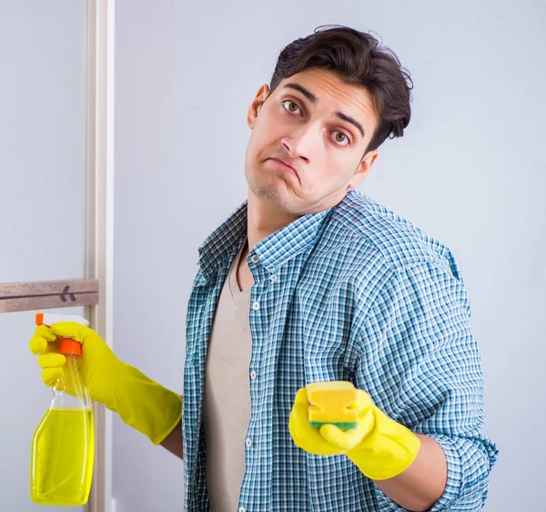 Νεαρός άνδρας καθαρίζει καθρέφτη στο ξενοδοχείο στο σπίτι — Φωτογραφία Αρχείου