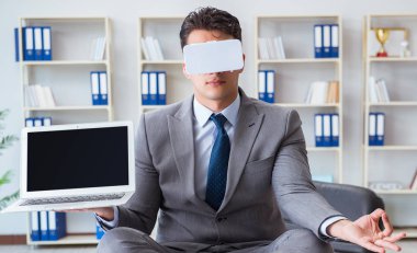 Sanal gerçeklikteki iş adamı VR gözlükleri masanın üstünde meditasyon yapıyor.