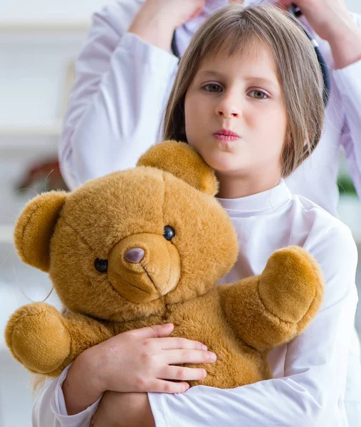 Donna medico femminile esaminando piccola ragazza carina con orso giocattolo — Foto Stock