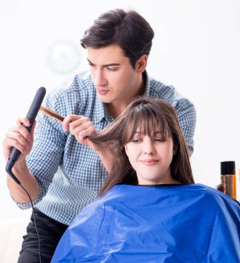 Erkek kuaför kadın için saç kesimi yapıyor.