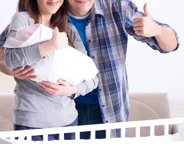 Young parents with their newborn baby near bed cot — Stock Photo, Image