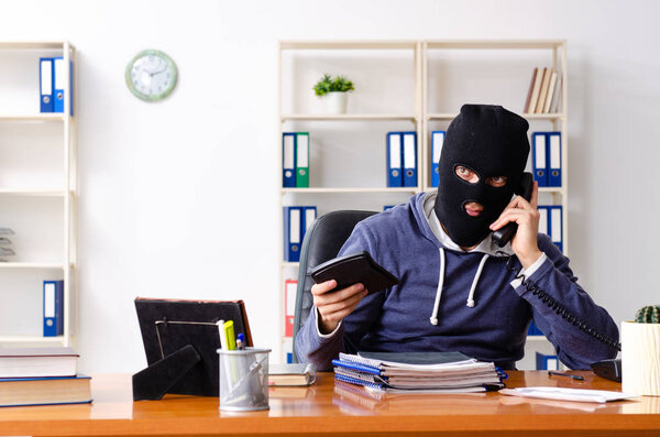 Male thief in balaclava in the office 