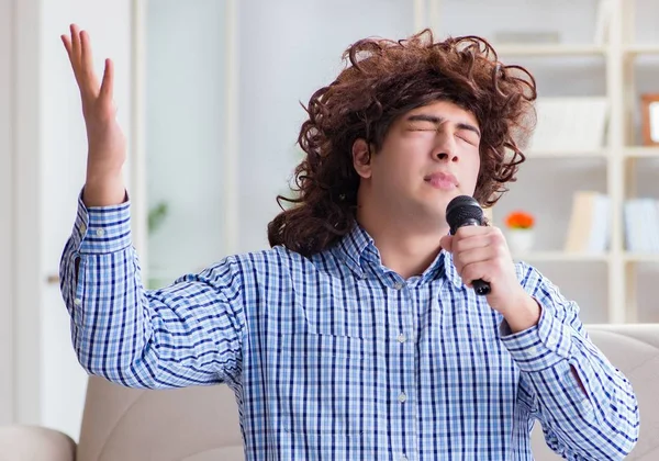 Sjov mand synger sange i karaoke hjemme - Stock-foto