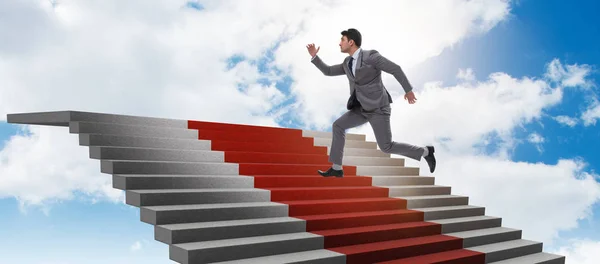 Mladý podnikatel stoupání po schodech a červený koberec do nebe — Stock fotografie