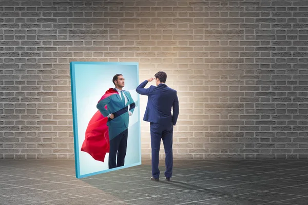 Businessman seeing himself in mirror as superhero