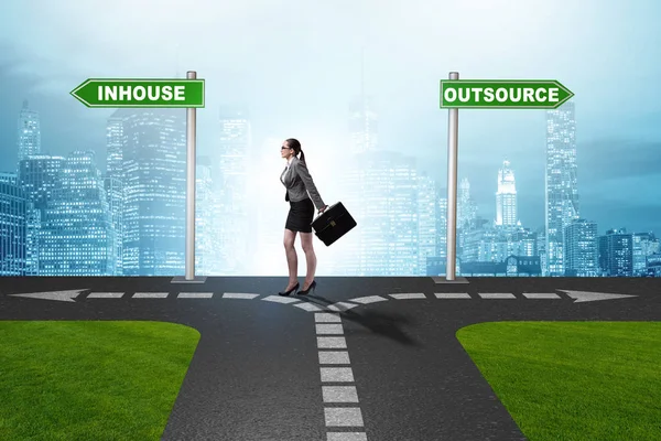 Businesswoman at crossroads deciding between outsourcing and inh — Stock Photo, Image