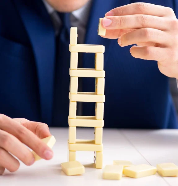 Genç işadamı ofiste domino kulesi inşa ediyor. — Stok fotoğraf