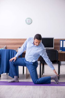 Genç yakışıklı işadamı iş yerinde egzersiz yapıyor. 