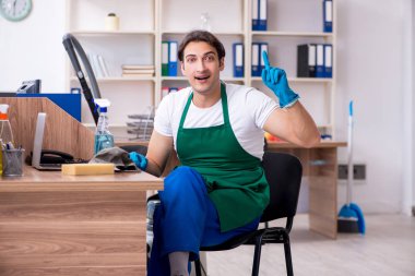 Genç yakışıklı müteahhit ofisi temizliyor. 