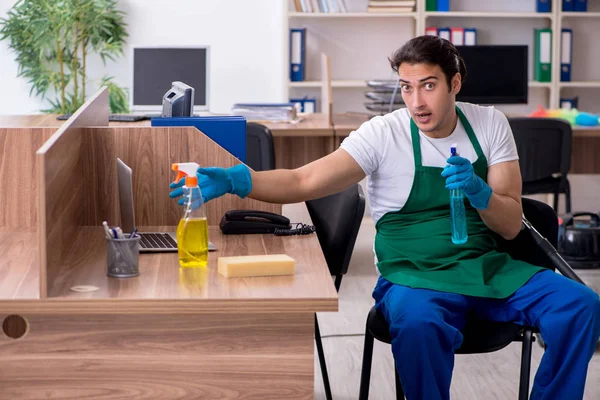 Genç yakışıklı müteahhit ofisi temizliyor. 