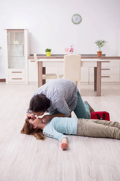 Casal jovem no conceito de primeiros socorros em casa — Fotografia de Stock