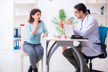 Orta yaşlı bir kadın, erkek doktor stomatoloğu ziyaret ediyor.