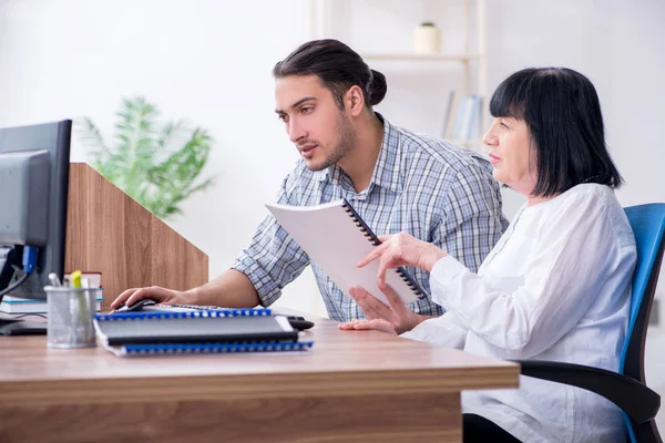 Junge männliche Mitarbeiter erklären alten Kolleginnen, wie sie zu uns kommen — Stockfoto