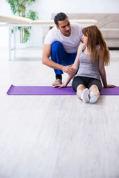 Männlicher Physiotherapeut macht Übungen mit verletzter Frau am Boden — Stockfoto