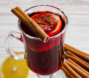 Haşlanmış şarap, yılbaşı masasında servis edilen bardaklarda parlıyor.