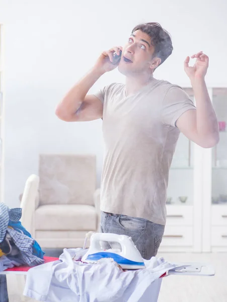 Marido desatento queimando roupas enquanto passa a ferro — Fotografia de Stock