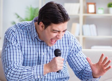 Evde karaoke yapan komik adam.