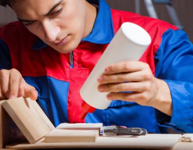 Genç adam ahşap parçaları DIY konseptinde yapıştırıyor.