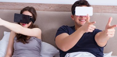 Yatakta sanal gerçeklik gözlüklü eş ve koca.