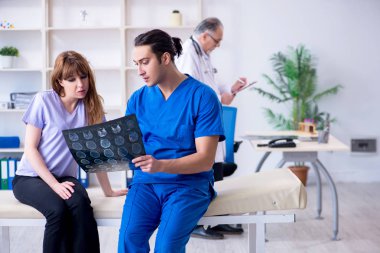 İki doktor genç kadını muayene ediyor. 