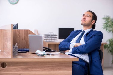 Genç yakışıklı işadamı ofiste çalışıyor. 