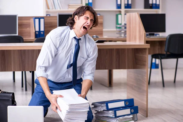 Jonge mannelijke werknemer en te veel werk op kantoor — Stockfoto