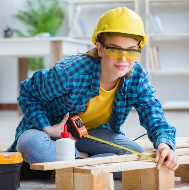 Tamirci kadın marangoz ahşap döşemeleri kesiyor.