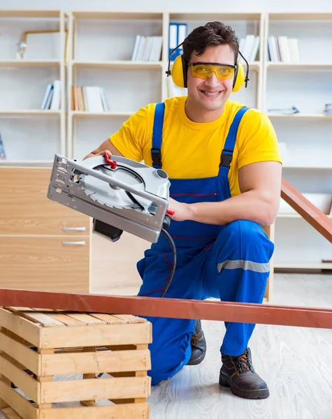 Reparador carpintero cortando aserrar una tabla de madera con un circuito —  Fotos de Stock