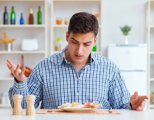 Fiatal férj eszik íztelen étel otthon ebédre — Stock Fotó
