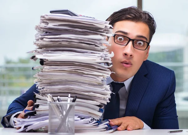 Бизнесмен с кучей бумажных документов в офисе — стоковое фото