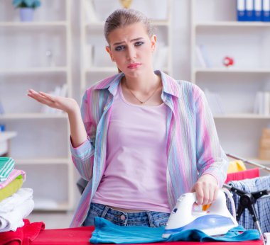 Üzücü kadın evde kıyafetleri ütülüyor.