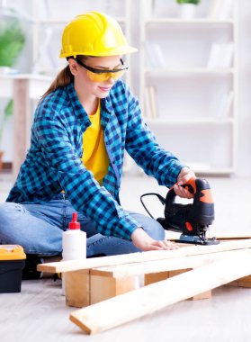 Tamirci kadın marangoz ahşap döşemeleri kesiyor.