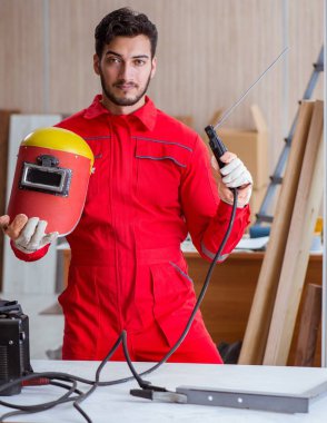 Kaynak tabancası elektrot ve kask takan genç bir tamirci.
