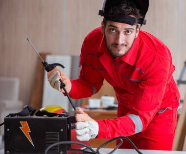 Kaynak tabancası elektrot ve kask takan genç bir tamirci.