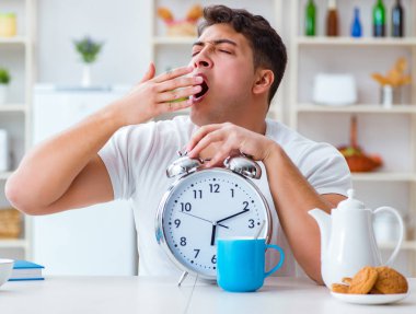 Çalar saati olan bir adam kahvaltıda uyuyakalıyor.