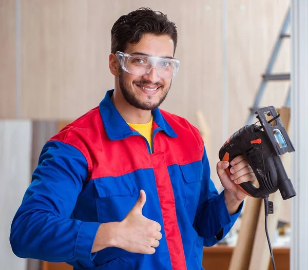 Jovem reparador trabalhando com uma serra elétrica — Fotografia de Stock