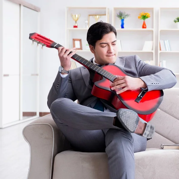 ビジネスマンは家でギターを弾く — ストック写真