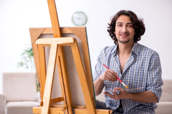Молодой красивый мужчина наслаждается живописью дома — стоковое фото