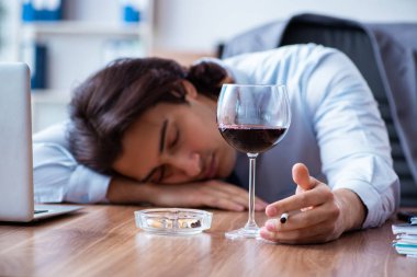 İş yerinde alkol ve sigara içen bir erkek işçi.