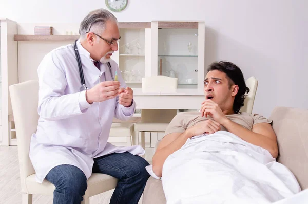 Old male doctor visiting young male patient