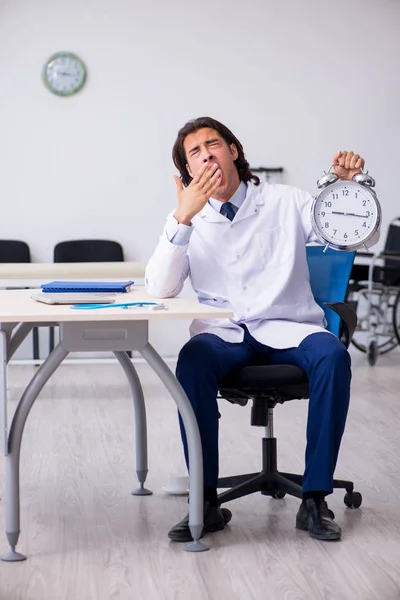 Joven médico masculino en concepto de gestión del tiempo —  Fotos de Stock