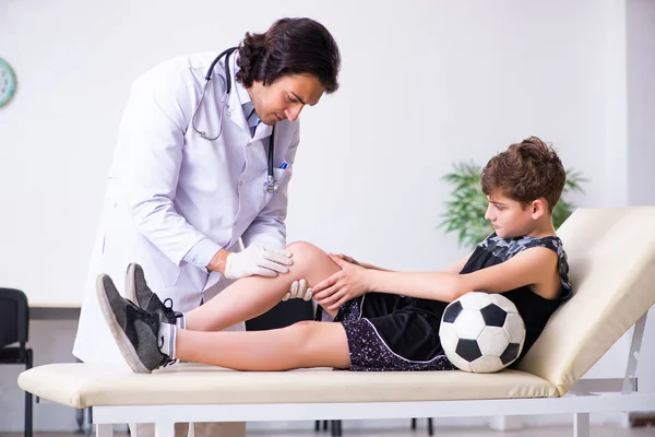 Niño jugador de fútbol visitando joven médico traumatólogo — Foto de Stock