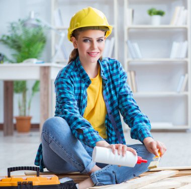 Tamirci kadın marangoz ahşap döşemeleri kesiyor.