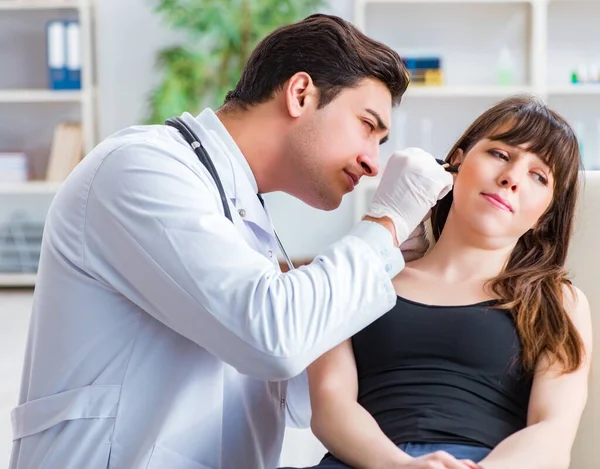 Doktor muayene sırasında hastaların kulaklarını kontrol ediyor.