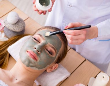 Yüz maskeli, spa sağlık konsepti olan genç bir kadın.