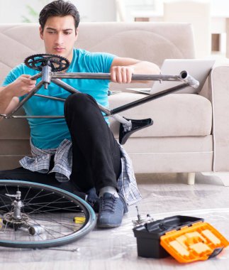 Evde bisiklet tamir eden genç bir adam.