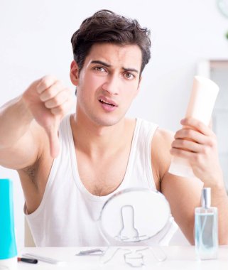 Genç yakışıklı adam aynaya bakıyor.