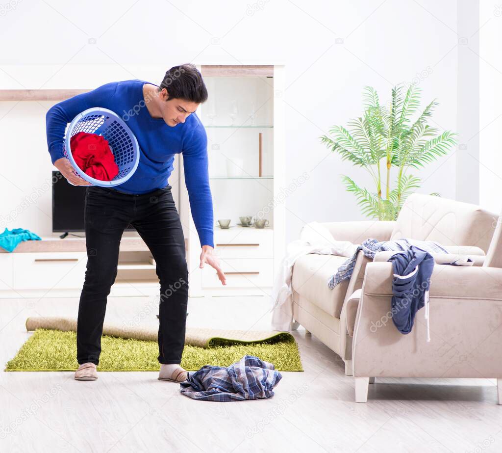 Young man collecting dirty clothing for laundry