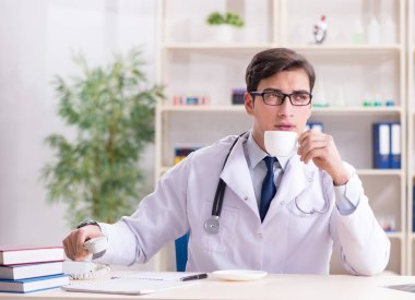 Genç doktor ofiste oturuyor.